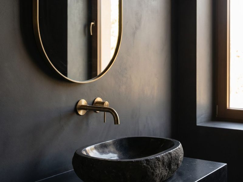 Lavabo escuro com cuba de pedra São Gabriel e metais dourados